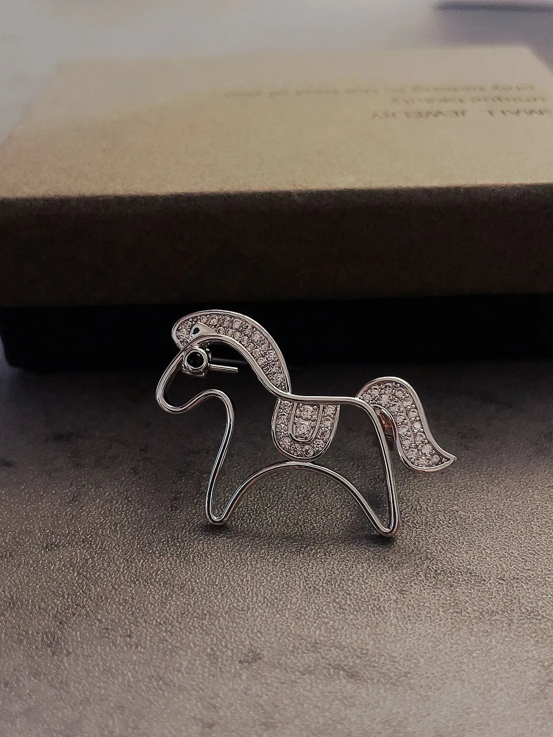 Golden pony brooch worn